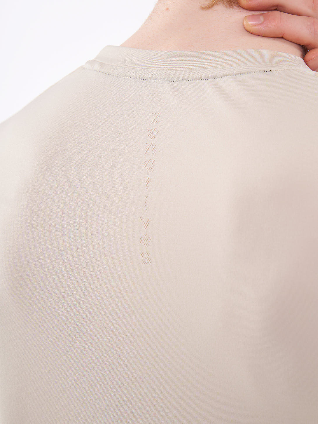 A Man Wearing White Sand Color Unisex Seamless Melange T-Shirt. Enhanced Comfort
