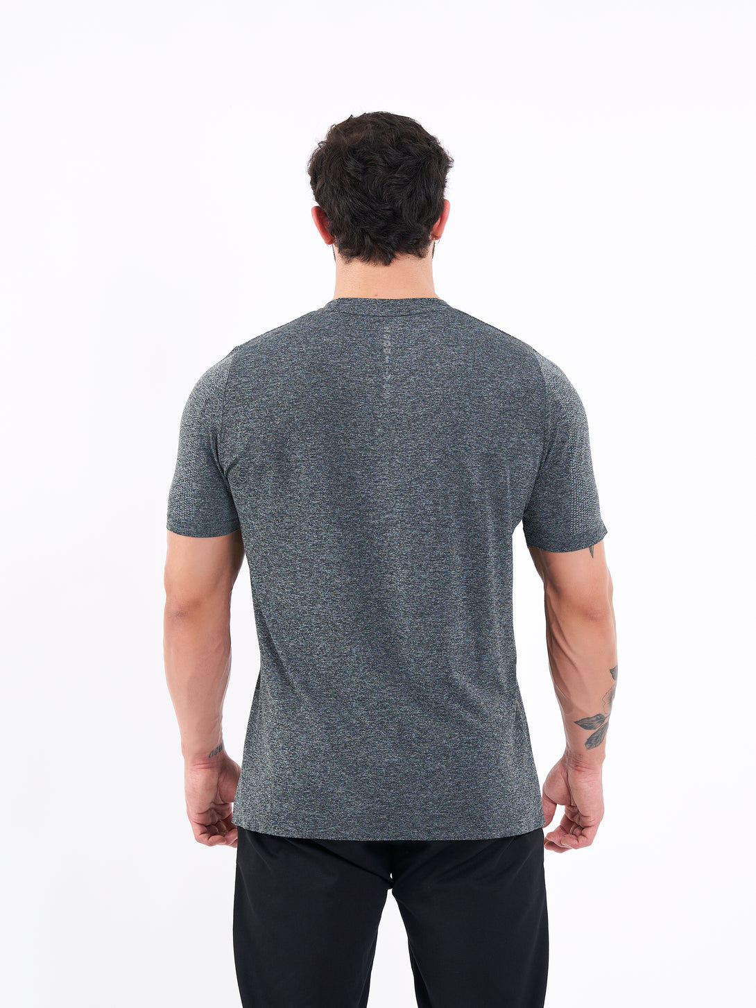 A Man Wearing Deep Black Color Unisex Seamless Melange T-Shirt. Enhanced Comfort