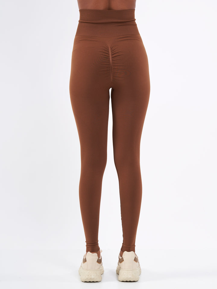 A Women Wearing Toffee Color Zen Confidence Seamless Compressive Leggings. Body-Shaping