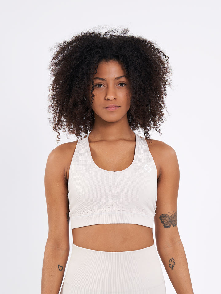 A Woman Wearing White Sand Color Seamless Ribbed Mid-Impact Sports Bra Without Padding Flexible