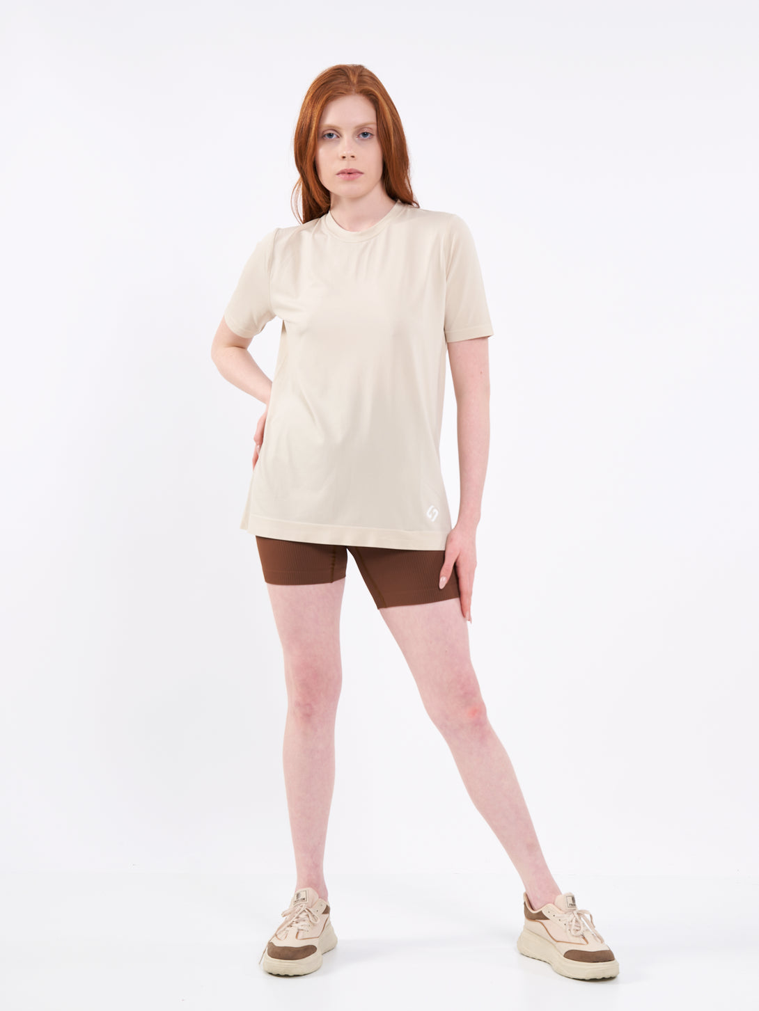 A Woman Wearing White Sand Color Unisex Seamless Melange T-Shirt. Enhanced Comfort