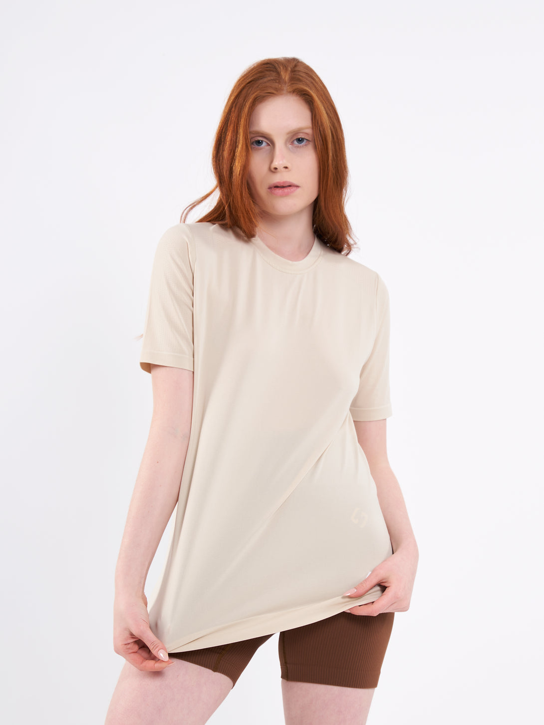 A Woman Wearing White Sand Color Unisex Seamless Melange T-Shirt. Enhanced Comfort